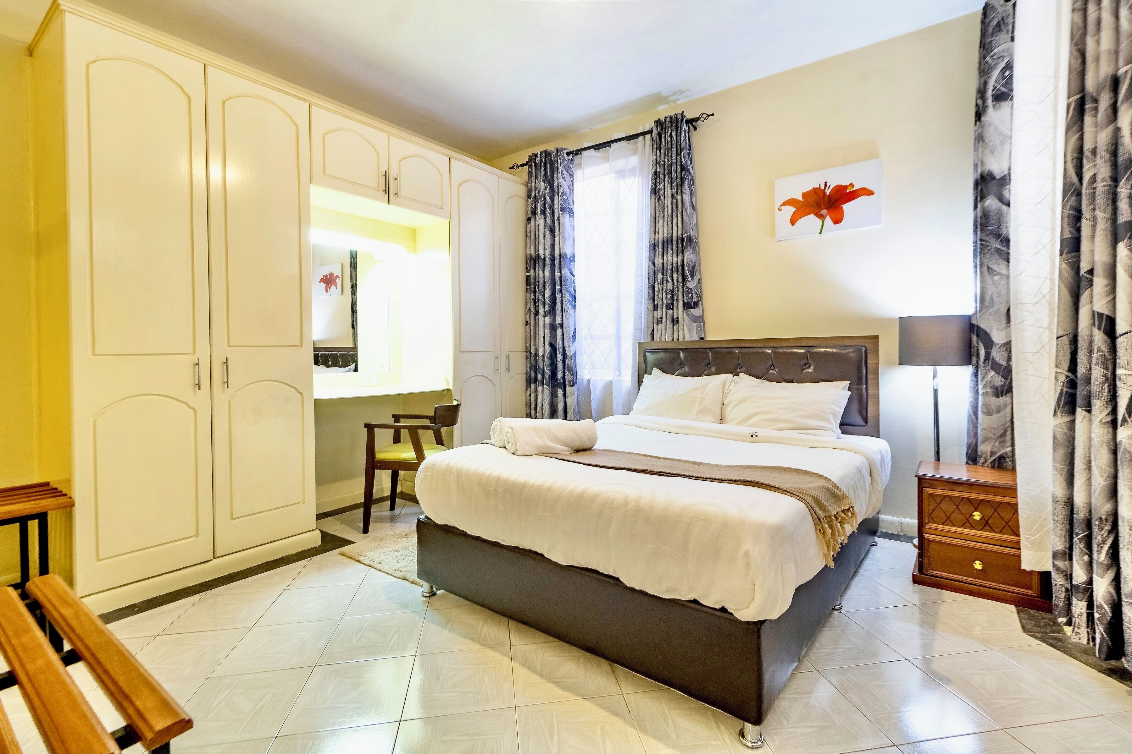 A bedroom with a bed, a wardrobe, a desk, and a chair.