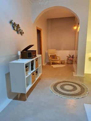 A hallway with a white console table, a chair, a rug, and a decorative wall piece. - Villa Paradise in Hammamet sleeps 12 with swimming pool (heated at extra cost) (Hammamet)