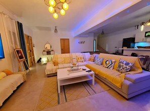 A living room with a sofa, coffee table, and a TV. - Villa Paradise in Hammamet sleeps 12 with swimming pool (heated at extra cost) (Hammamet)