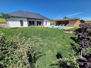 A modern house with a swimming pool, a covered outdoor seating area, and a well-maintained lawn.