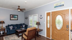 A living room with a blue sofa, wooden chair, and a wooden door with glass panels. - Family Cottage Near Cedar Point and Sports Center! (Huron)