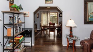 A dining area with a table and chairs, a bookshelf, and a lamp. - Family Cottage Near Cedar Point and Sports Center! (Huron)