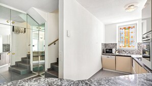 Cocina moderna con encimera de granito, microondas, lavavajillas y ventana con diseño de vitral.