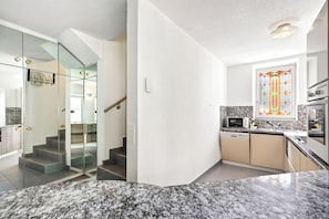 Cocina moderna con encimera de granito, microondas, lavavajillas y ventana con diseño de vitral.