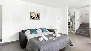 Una habitación de hotel moderna con una cama, una mesita de noche, un cuadro y una escalera.