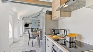 Et moderne køkken med indbygget komfur, et spiseområde med bord og stole, og udsigt til opholdsstuen.