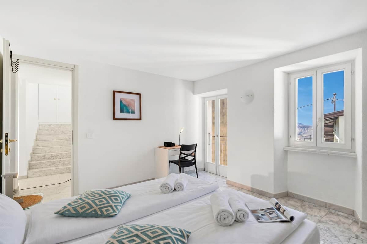 Habitación de hotel con cama, escritorio, silla y vista al exterior.