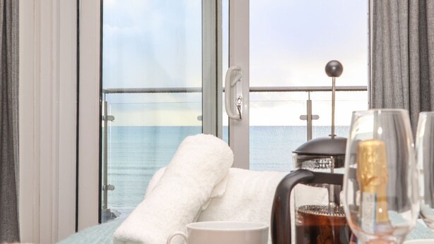 A room with a balcony, a coffee maker, a cup, and a glass.