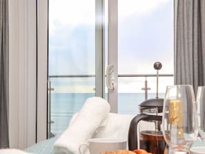 Una habitación con balcón, cafetera, taza y vaso.