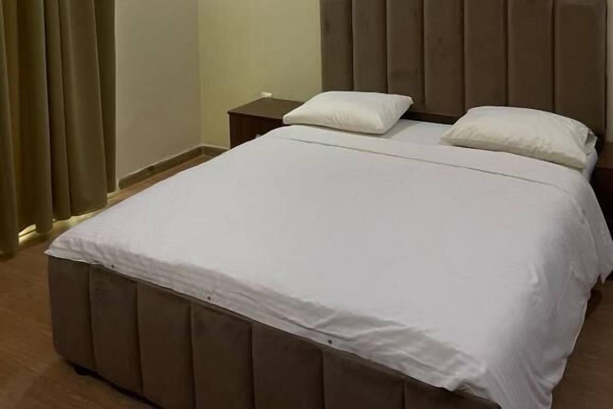 Ein Schlafzimmer mit Bett, Nachttischen und einer Deckenleuchte.