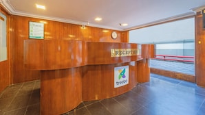 En receptionsdisk med en klocka, en skylt med en logotyp och utsikt över omgivningen.