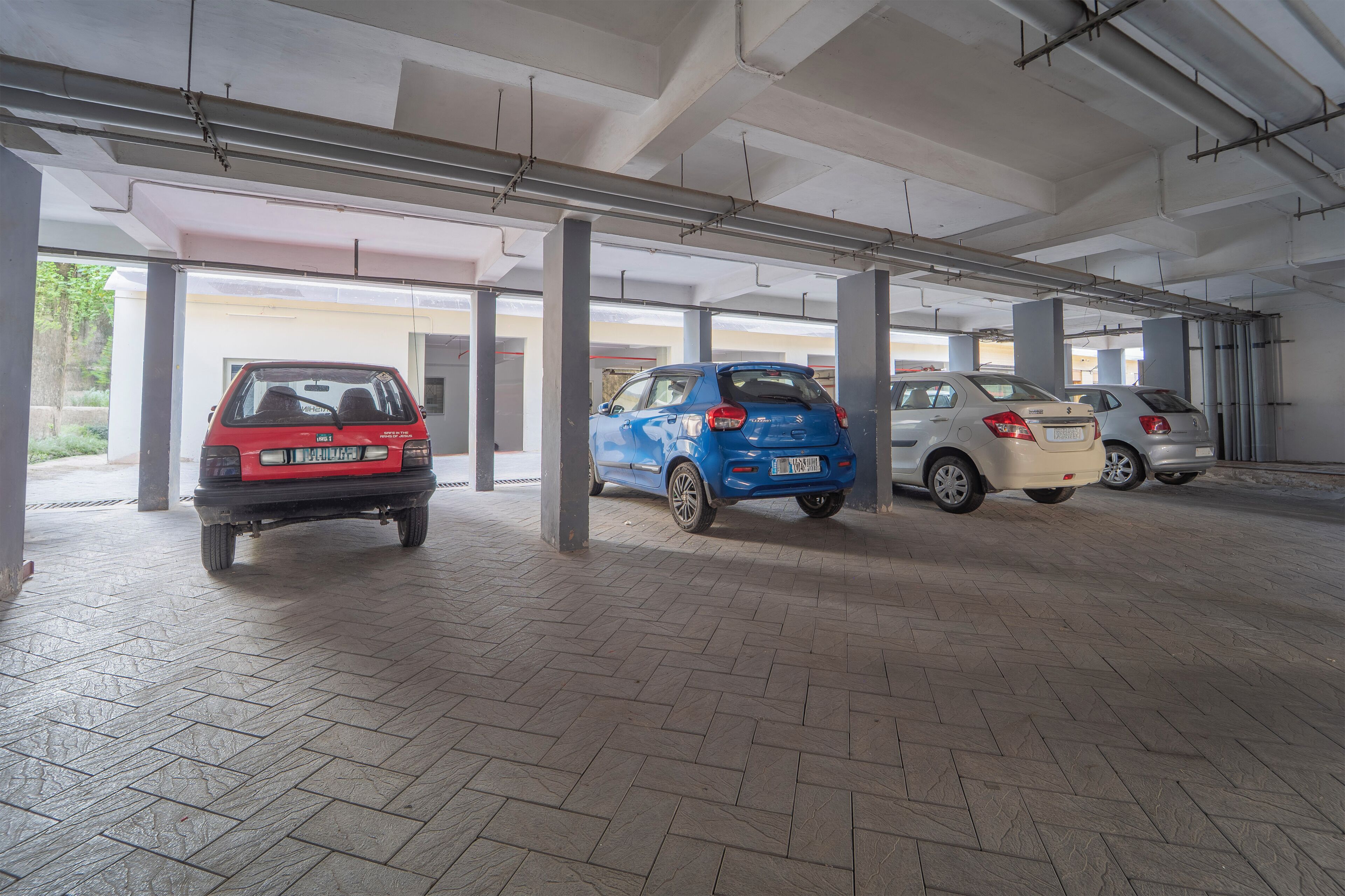 A parking garage with four cars parked in a row.