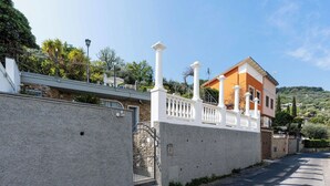Eine Wohnstraße mit einer weißen Mauer, einem verschlossenen Eingang und einem Haus mit einem Balkon.