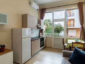 Eine kleine Küche mit Kühlschrank, Herd und einem Essbereich mit Tisch und Stühlen.
