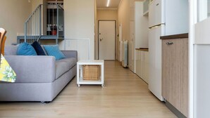 En moderne lejlighed med en grå sofa, et lille bord, en radiator og en trappe til et højere niveau.