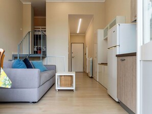Eine moderne Wohnung mit einem grauen Sofa, einem kleinen Tisch, einer Heizung und einer Treppe, die in eine höhere Ebene führt.