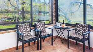 Una habitación con ventanas amplias, dos sillas, una mesita y una botella de champán.