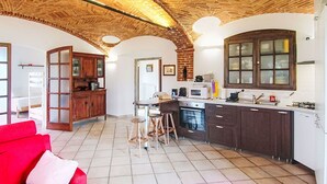 Una cocina con techo de ladrillo, armarios de madera, horno empotrado y una ventana.