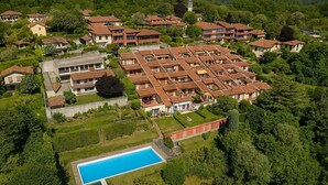 Vista aerea di una zona residenziale con piscina, circondata da case con tetti in tegole rosse.