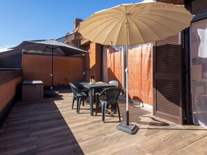 Eine Terrasse im Freien mit Tisch, Stühlen und einem großen Sonnenschirm, sowie ein Holzdeck.