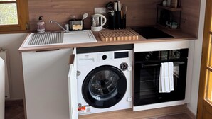 A compact kitchen with a washing machine, a microwave, and a built-in oven. - Your Alpine Retreat — Spa Treatments, Fine Dining, and Adventure (Saint-Martin-d'Uriage)