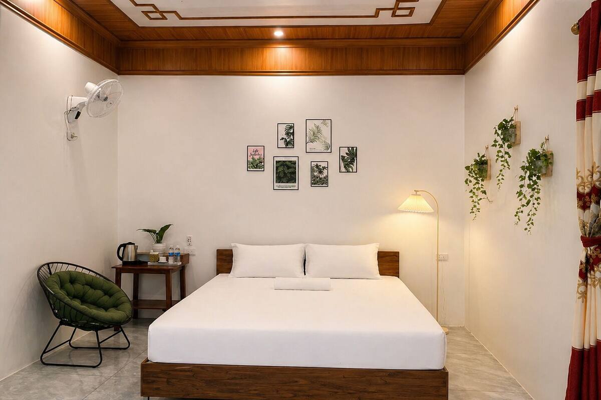 A bedroom with a bed, a chair, a nightstand, a lamp, and wall art.