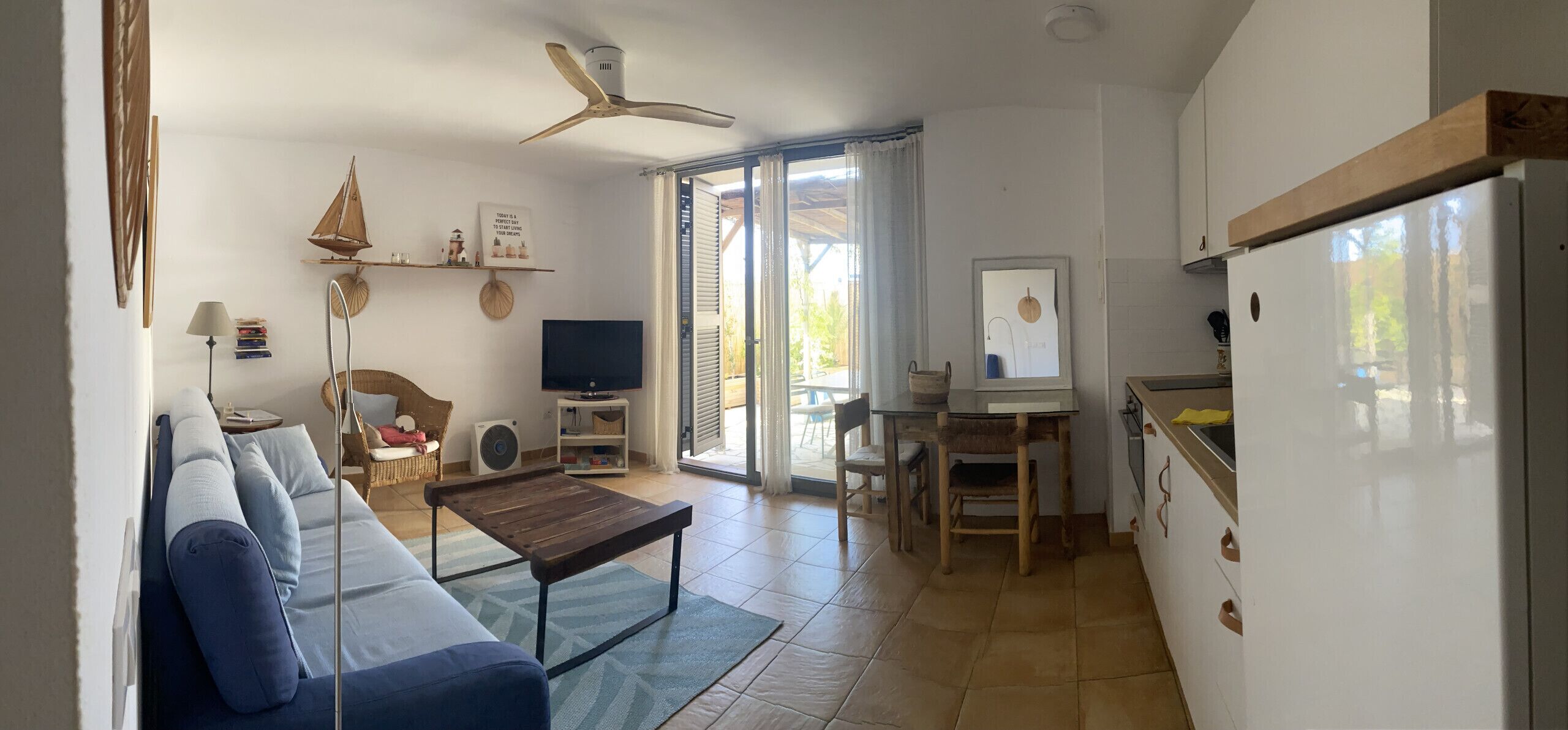 Een woonkamer met een bank, salontafel, televisie en een eethoek met stoelen en een tafel.