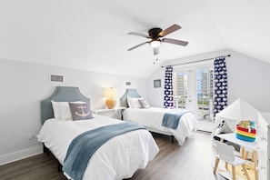 A bedroom with two beds, a ceiling fan, a desk with a chair, and a window with curtains. - Multi-Family Home | Short Walk to Beach (Gulf Shores)