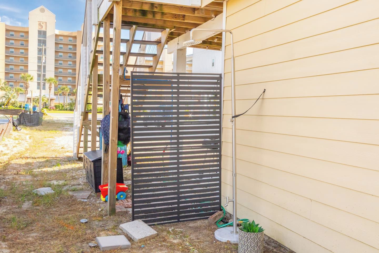 Un espace extérieur clos, agrémenté d’une pergola en bois, d’un portail noir et d’une petite plante en pot.