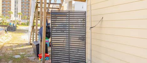 A gated outdoor area with a wooden pergola, a black gate, and a small potted plant.