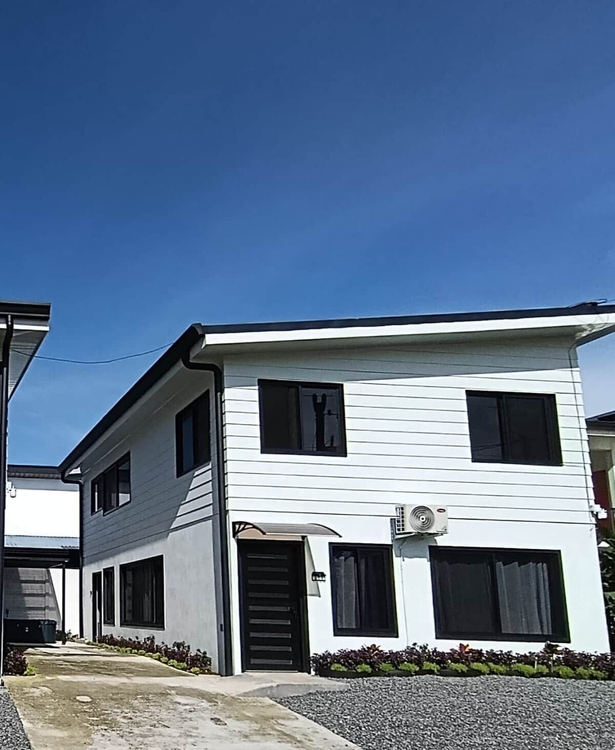A two-story building with a flat roof, a front door, and a small porch.