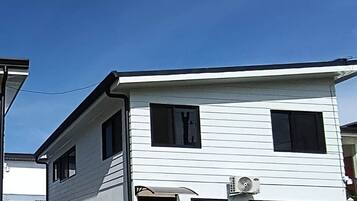 A two-story building with a flat roof, a front door, and a small porch.
