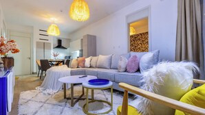 A modern living room with a sofa, a coffee table, and a dining area in the background. - Nova 2-bedroom apartment in Nairobi (Nairobi)