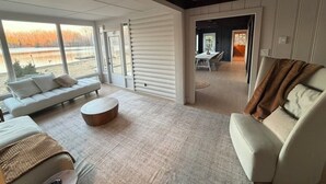 Ein geräumiger Wohnbereich mit einer Couch, einem runden Couchtisch und Seeblick durch große Fenster.