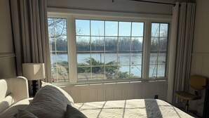 Ein Schlafzimmer mit großem Fenster, einem Bett und einem Sessel.