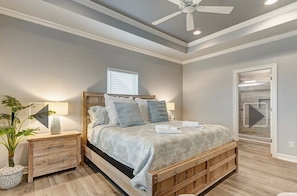 A bedroom with a wooden bed, bedside tables, a ceiling fan, and a window. - 3-bedroom/2 bath house in the beautiful Sandy Shores neighborhood. (Bolivar Peninsula)
