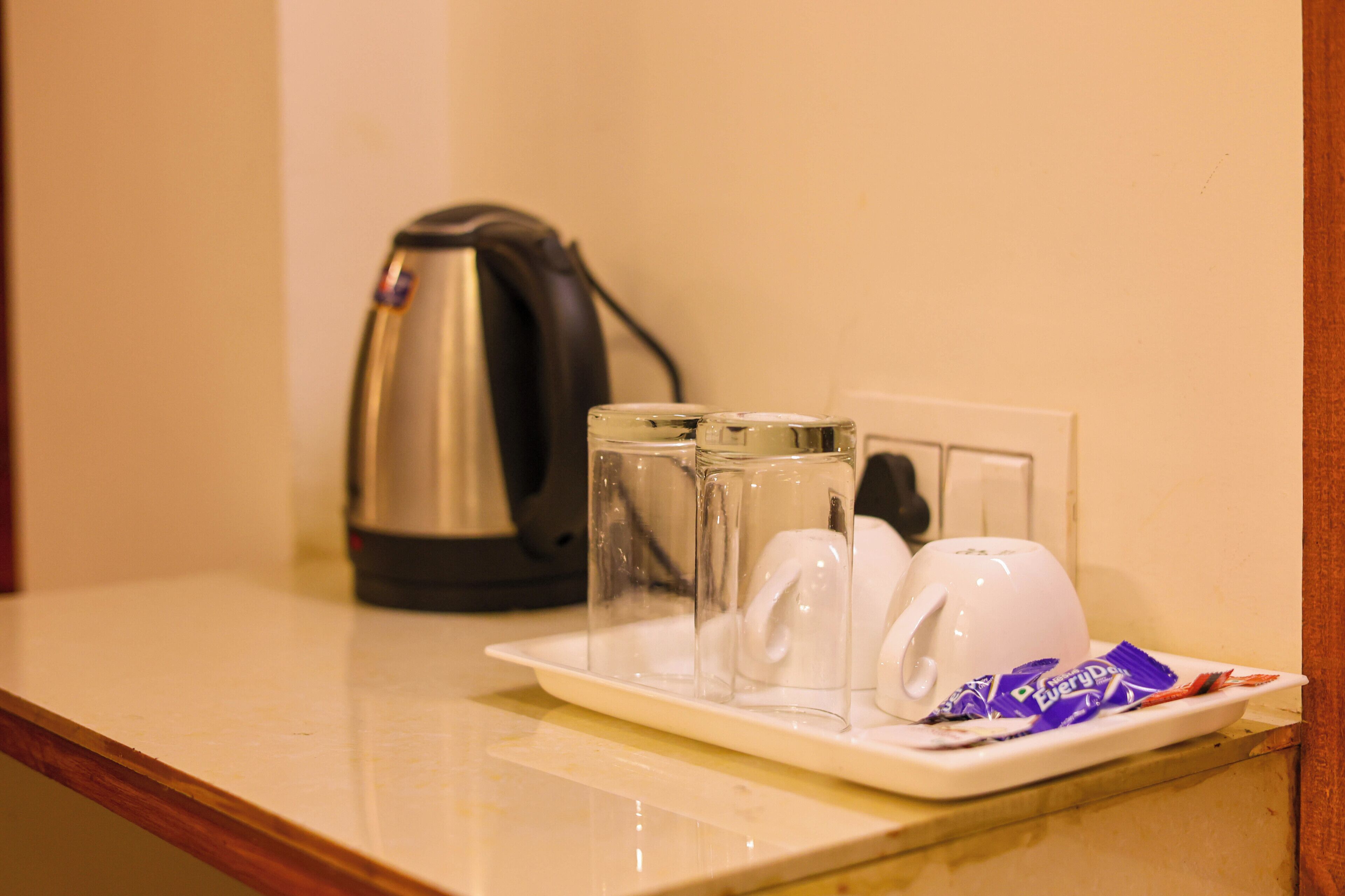 A tray with a white mug, a glass, and a packet of chocolate on a hotel counter.