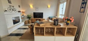 A living room with a fireplace, a television, a sofa, and a coffee table. - Charming flat with cozy terraces just a stone's throw from the beach (Calahonda)