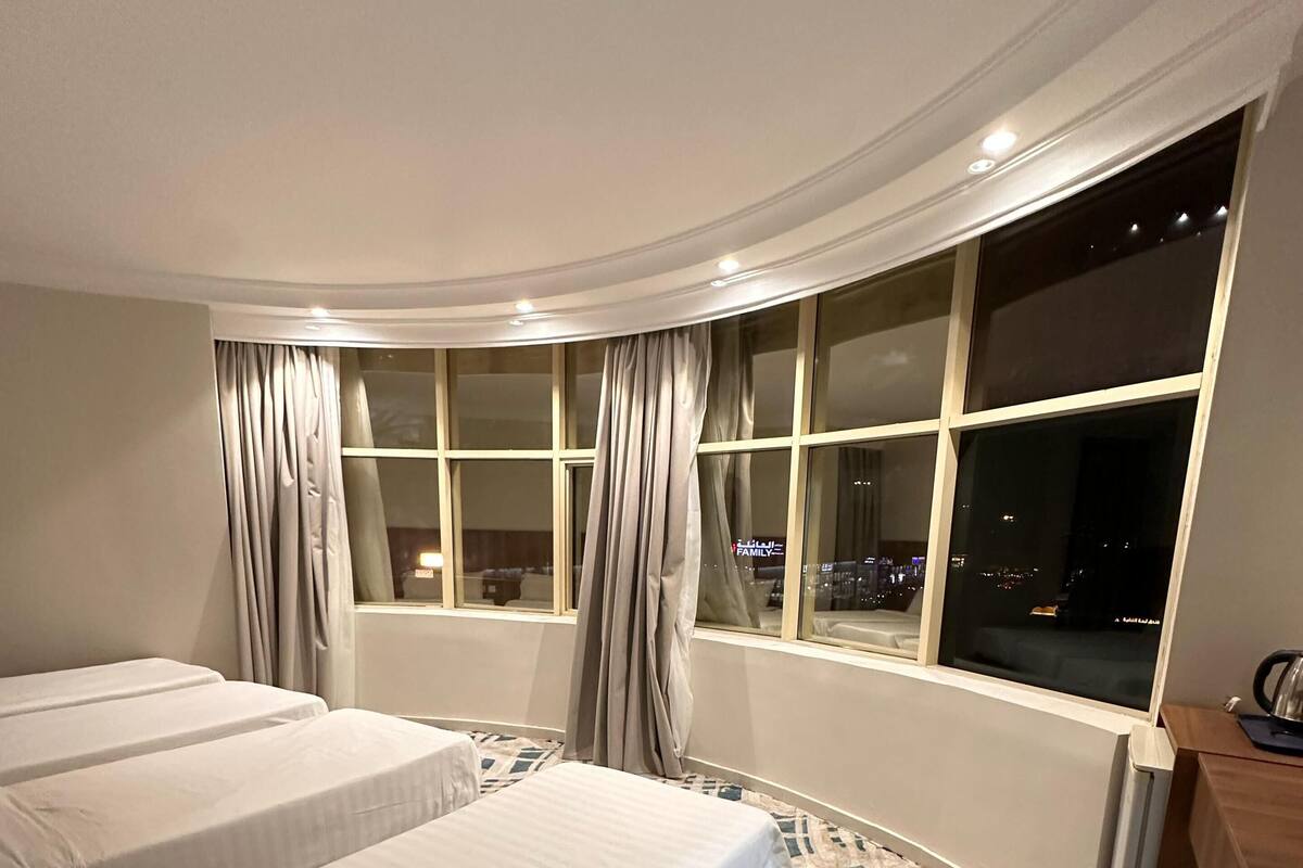 A hotel room with two beds, a desk, a chair, a window with curtains, and a patterned carpet.