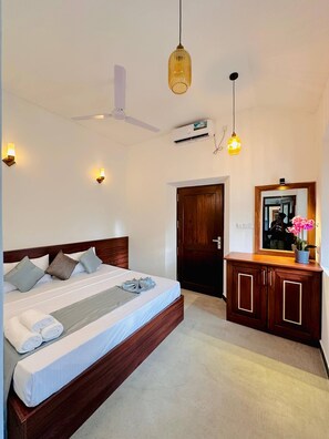 A bedroom with a bed, bedside lamps, a ceiling fan, an air conditioning unit, a wooden wardrobe, and a mirror. - The Ridgecolonial Villa 10 min Walk to Beach (Ahangama)