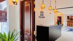 A reception desk with a logo, wooden door, potted plant, and hanging pendant lights. - The Ridgecolonial Villa 10 min Walk to Beach (Ahangama)