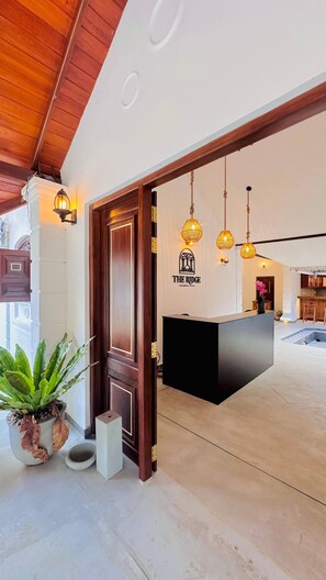 A reception desk with a logo, wooden door, potted plant, and hanging pendant lights. - The Ridgecolonial Villa 10 min Walk to Beach (Ahangama)