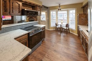 Uma cozinha com forno embutido, área de jantar com mesa e cadeiras, e janelas amplas.