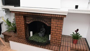 A brick fireplace with a statue, a potted plant, and a white wall. - Art House by Helen in Soroni Rhodes (Rhodes)