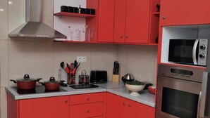 A kitchen with red cabinets, a stainless steel range hood, a microwave, and an oven. - Art House by Helen in Soroni Rhodes (Rhodes)