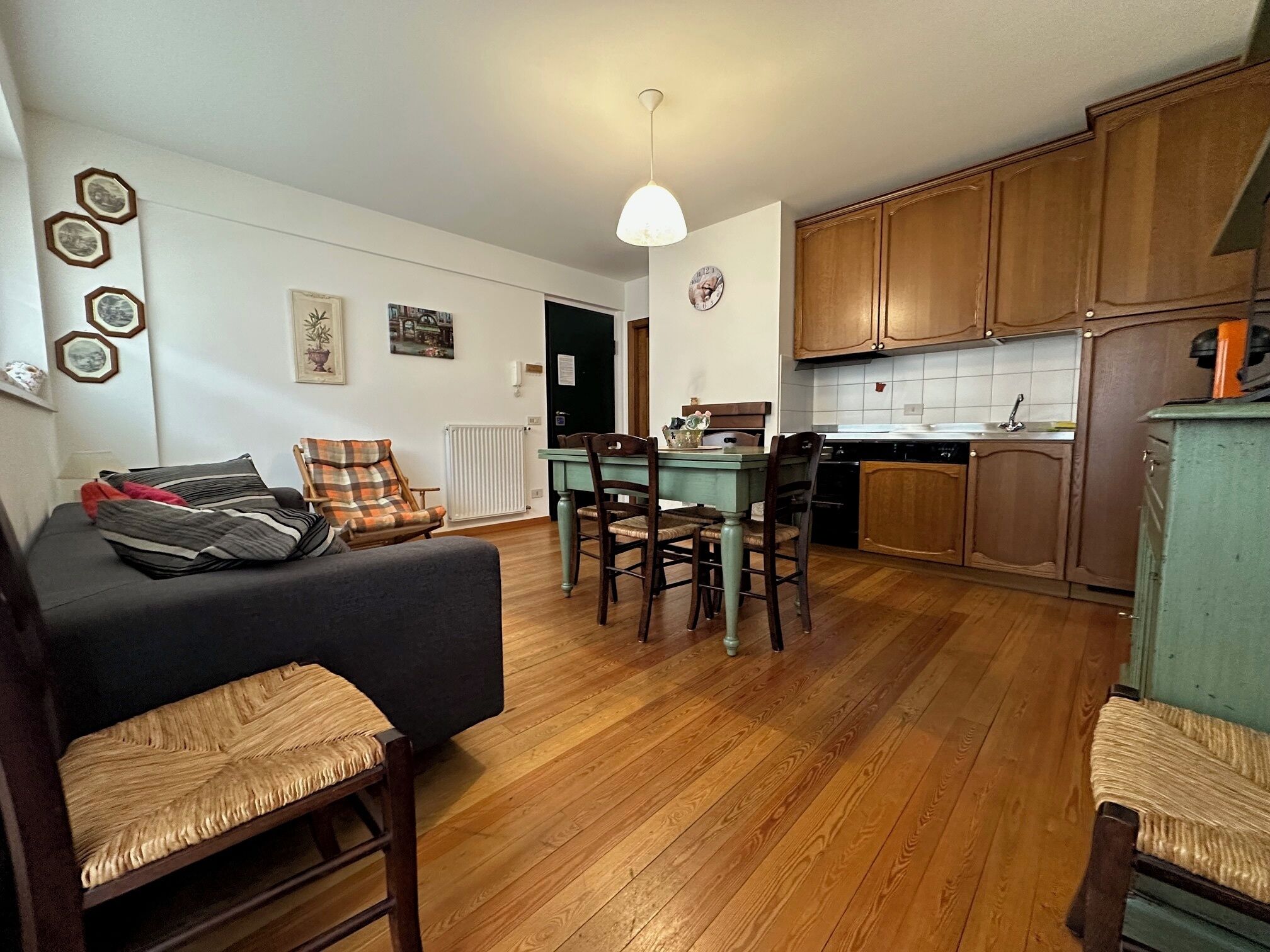 A compact living space with a dining area, wooden flooring, and a kitchenette.