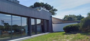 En moderne bygning med store glasfacader, træbeklædning og en græsplæde.