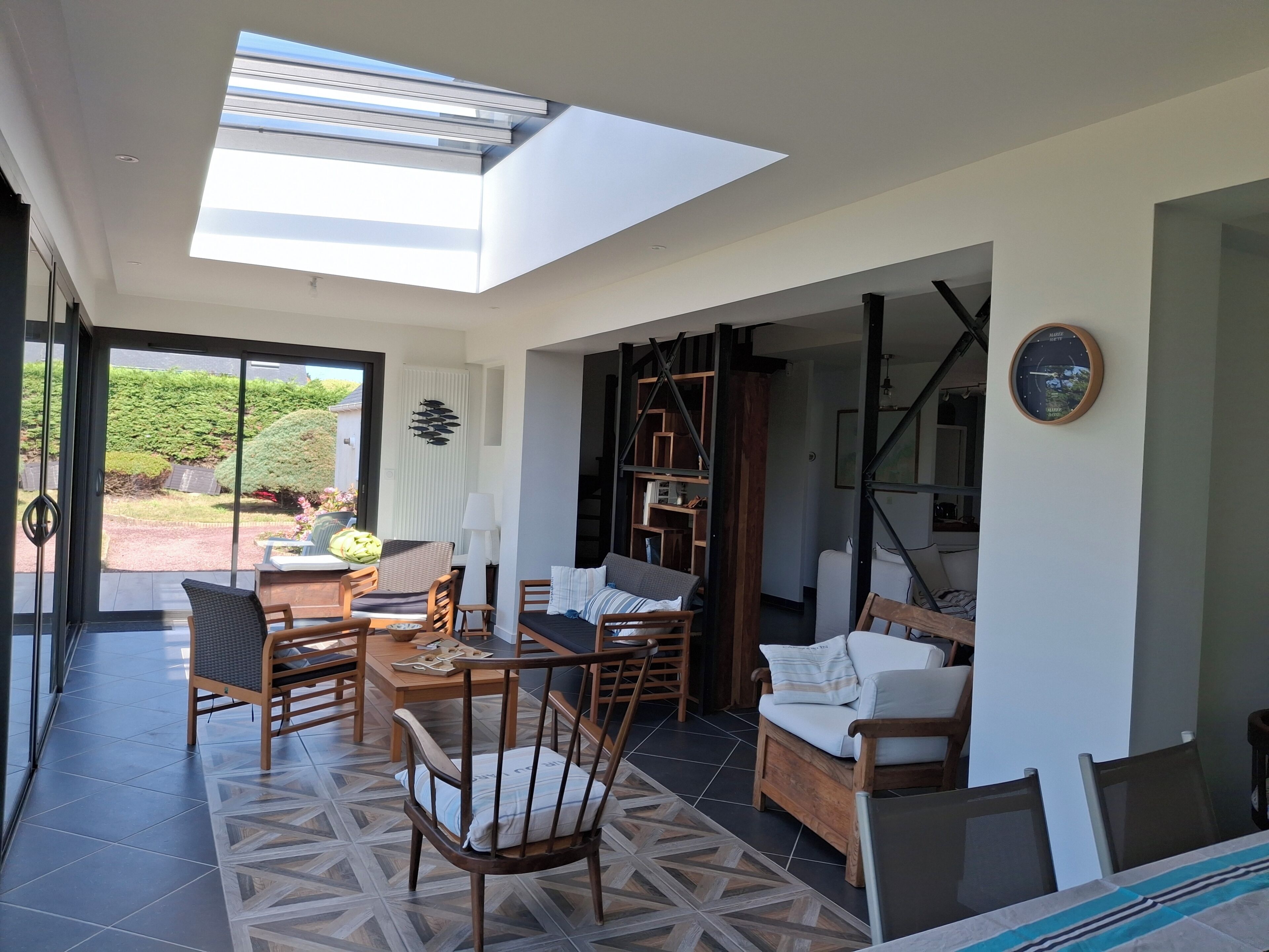 Una habitación amplia con tragaluces, un comedor con sillas y una mesa, y una zona de estar acogedora con cojines.