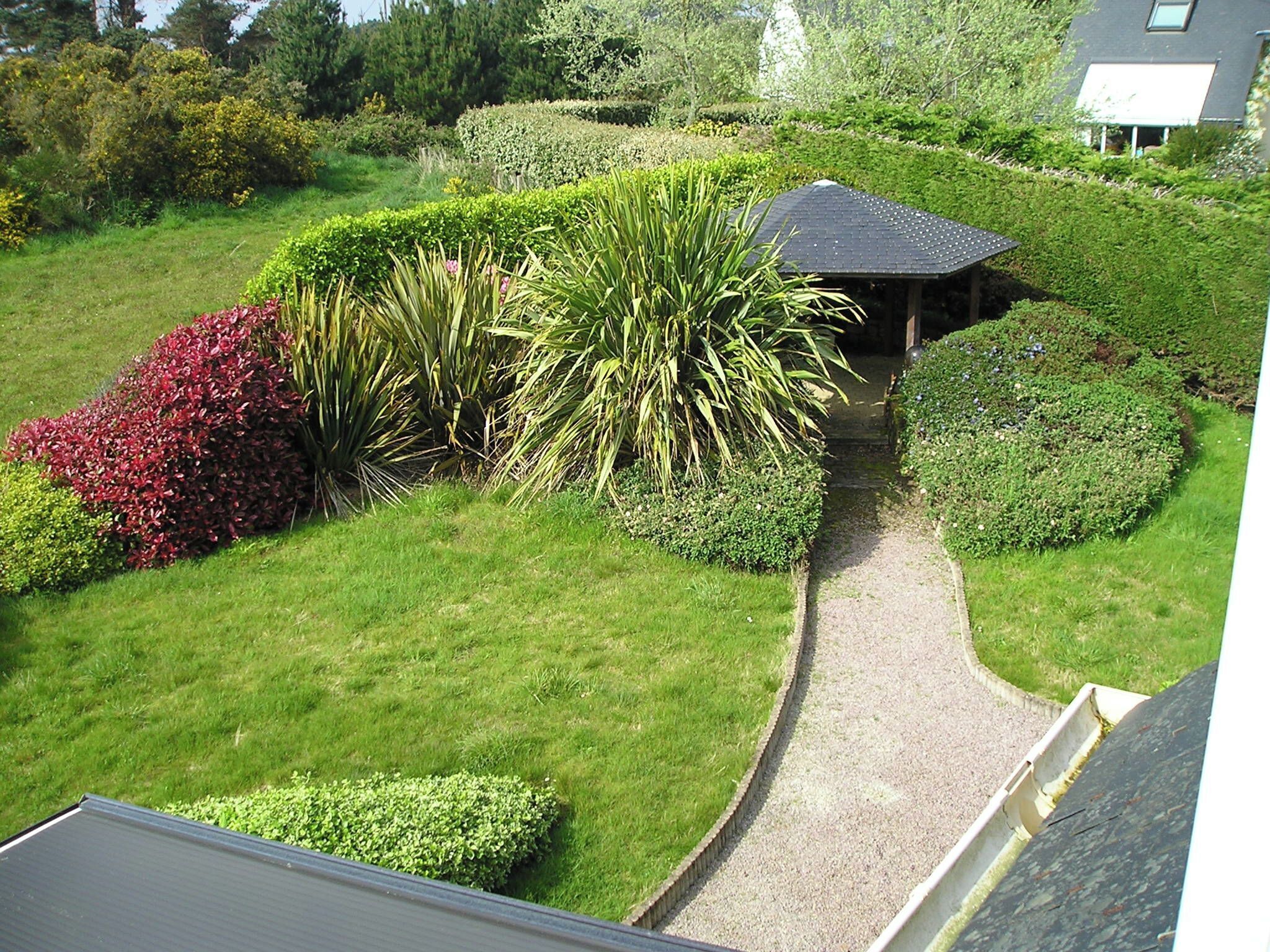 Ein gepflegter Garten mit einem Kiesweg, der zu einem Gartenpavillon führt.