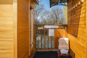 Der Saunagang: Holzvertäfelung, Glastür, Hinweisschild mit Saunabeschreibungen und ein Handtuch auf dem Boden.
